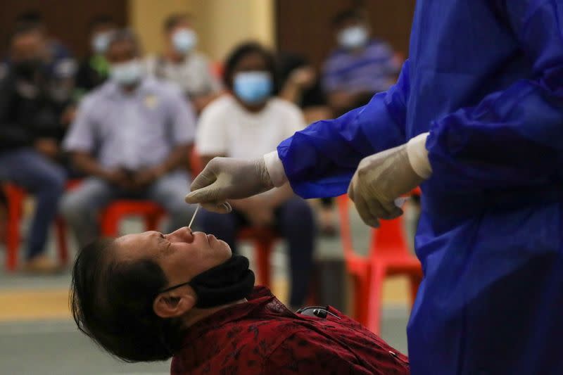 Medical worker collects a swab sample from a man to be tested for the coronavirus disease (COVID-19) in Petaling Jaya