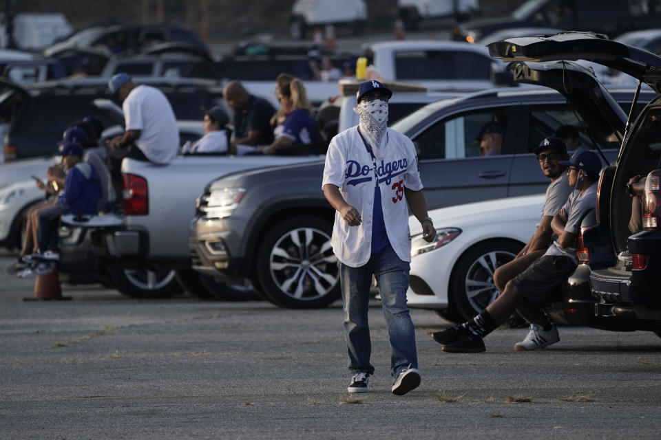 FILE - In this Oct. 20, 2020, file photo, fans sit in their cars outside of Dodger Stadium in Los Angeles to watch the television broadcast of Game 1 of baseball's 2020 World Series between the Los Angeles Dodgers and the Tampa Bay Rays. A backlog in coronavirus testing results hid a recent rise in infections in Los Angeles County, the county's top health official said Monday, Oct. 26, 2020, warning that fans gathering to watch recent championship sporting events may have increased the spread. (AP Photo/Ashley Landis, File)