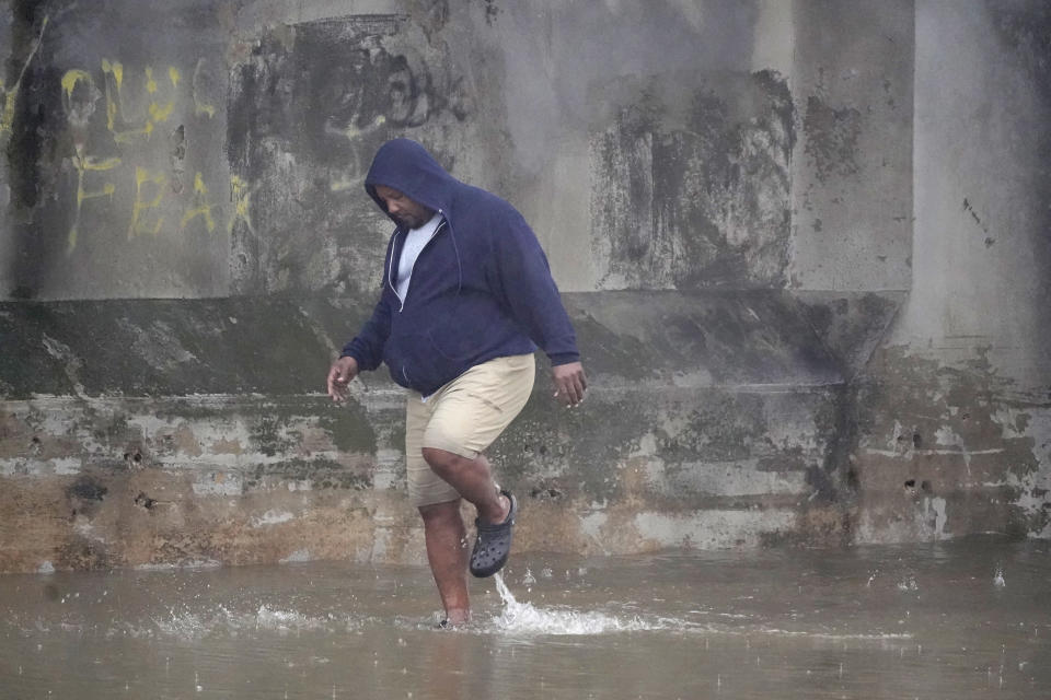 Semi-truck driver Steven Virgil walks in flood waters covering a closed highway in Dallas, Monday, Aug. 22, 2022. After checking the depth of the flash flood, Virgil decided to not drive across the water. (AP Photo/LM Otero)