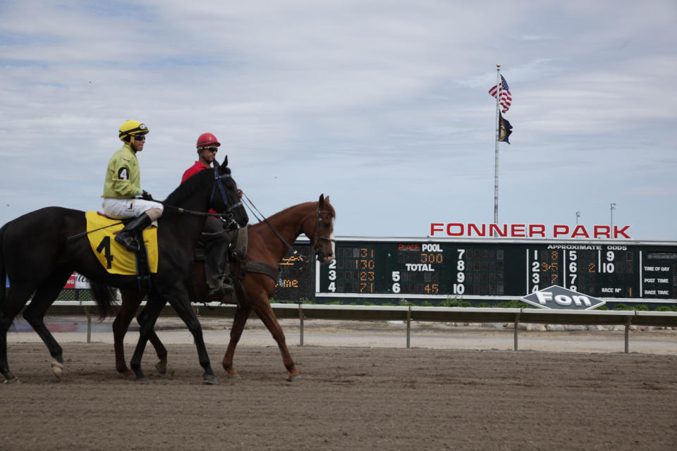 A jockey and handler ride their horses down the track between races at Fonner Park in Grand Island, Nebraska, on Friday, May 20, 2022. Horse tracks have been struggling for decades, but after Nebraska legalized casino gambling at the state's six licensed facilities, there's suddenly a lot of interest in them and some communities want to build their own. (AP Photo/Grant Schulte)