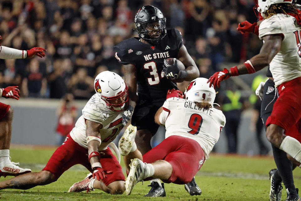 North Carolina State's Delbert Mimms III (34) is tackled by Louisville's Cam'Ron Kelly and Ashton Gillotte (9) during the second half of an NCAA college football game in Raleigh, N.C., Friday, Sept. 29, 2023. (AP Photo/Karl B DeBlaker)