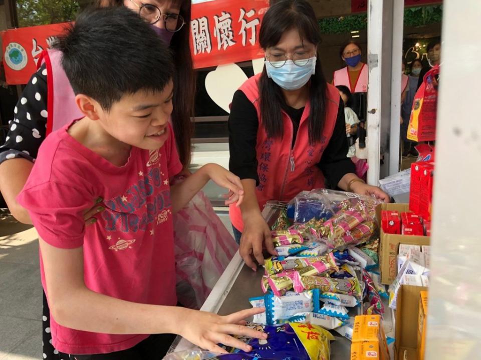 八里愛心教養院院生在志工阿姨的協助下於「行動超商車」開心地挑選餅乾等零食。　（記者吳瀛洲攝）