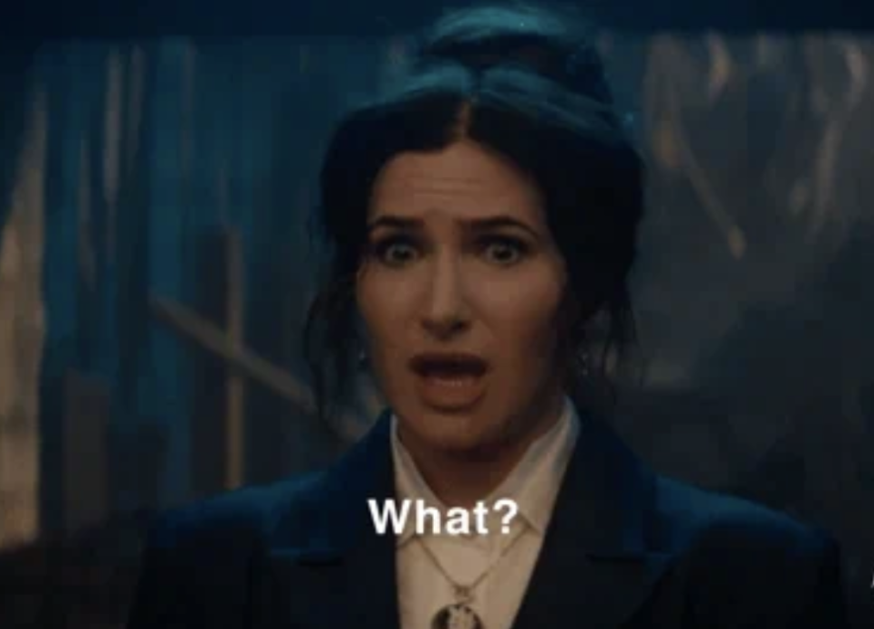 Kathryn Hahn as Agatha Harkness in "WandaVision," looking surprised with the caption "What?" visible beneath her