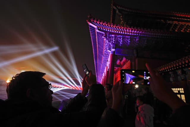 Visitors take photos of the Forbidden City illuminated with lights during the Lantern Festival in Beijing