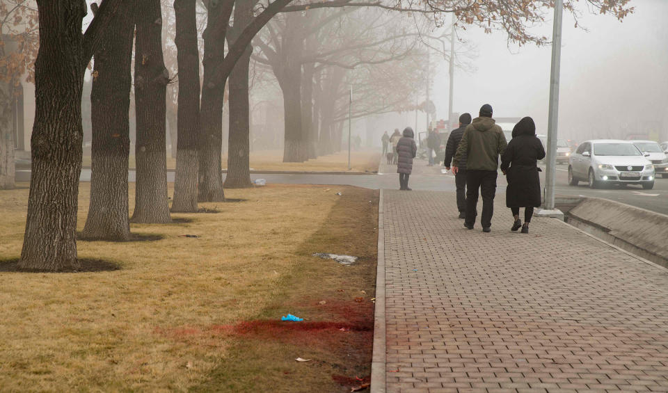 People walk past blood on a curbside lawn after violence that erupted following protests over hikes in fuel prices, in Almaty, Kazakhstan on Jan. 6, 2022.<span class="copyright">Alexander Bogdanov— AFP/Getty Images</span>