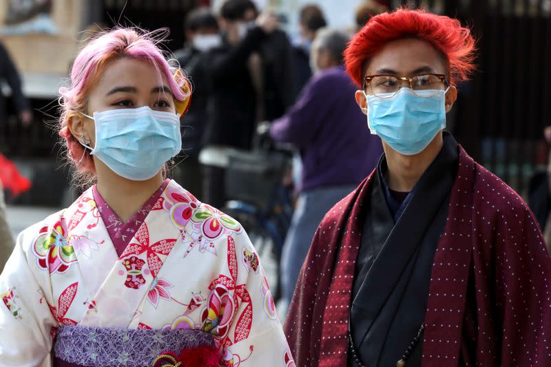 Turistas con kimono y máscaras protectoras visitan el Templo Sensoji en el distrito de Asakusa en Tokio, Japón