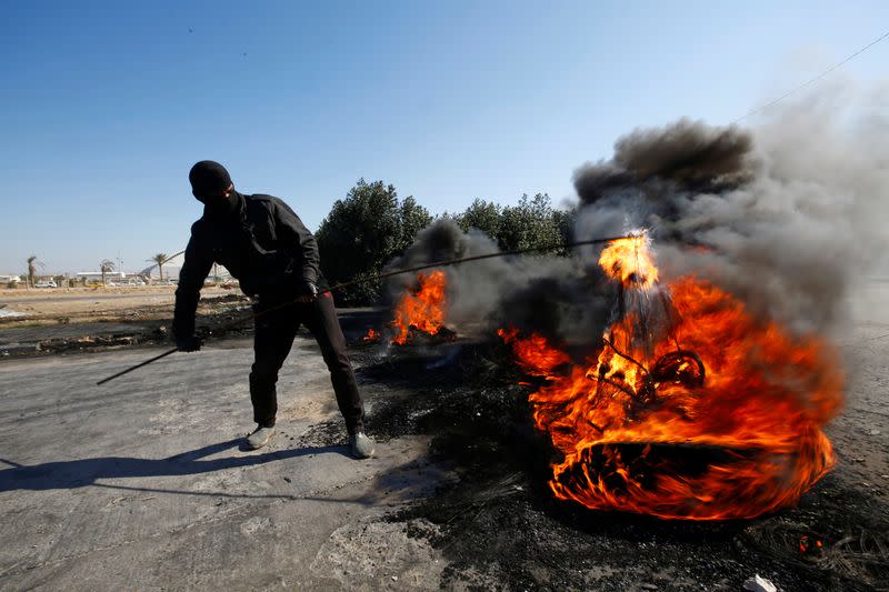 Iraqi demonstrator burns tires to block a road during ongoing anti-government protests in Najaf