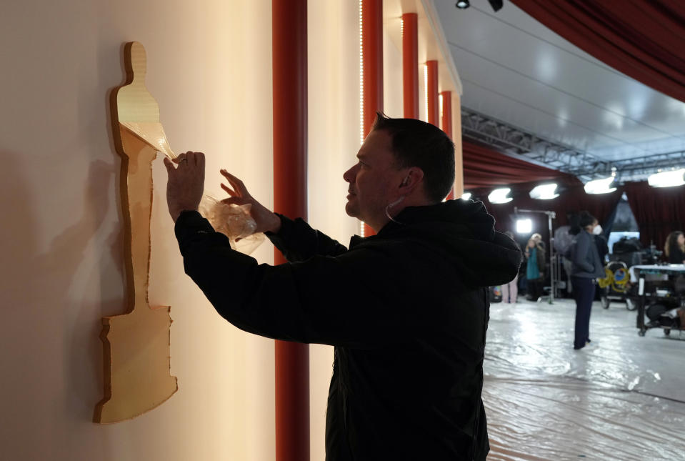 Art director Jerry Sonnenberg peels protective plastic off an Oscar decoration In preparation for Sunday's 95th Academy Awards, Friday, March 10, 2023, outside the Dolby Theatre in Los Angeles. (AP Photo/Chris Pizzello)