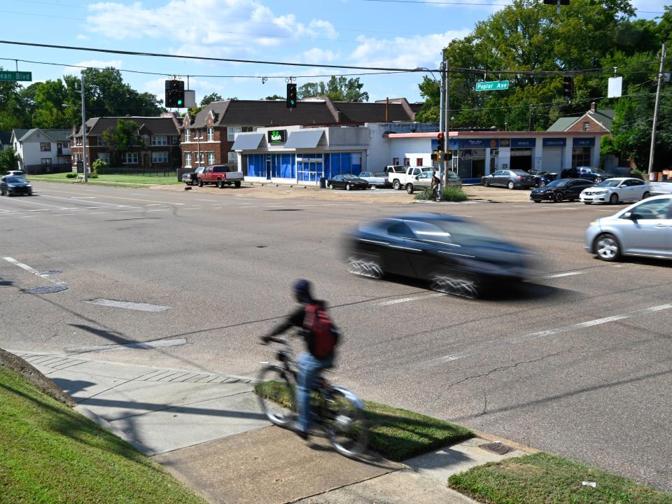 A bicyclist and motororists make their way down Poplar Ave. at the McLean Blvd. intersection Thursday, Sept. 8, 2022, a day after a gunman opened fire on people in the area.