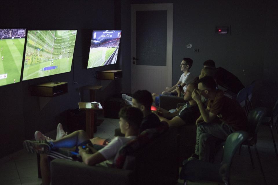 Unos jóvenes juegan a videojuegos en una sala de ocio de Ballsh. (Foto: Daniel Cole / AP).