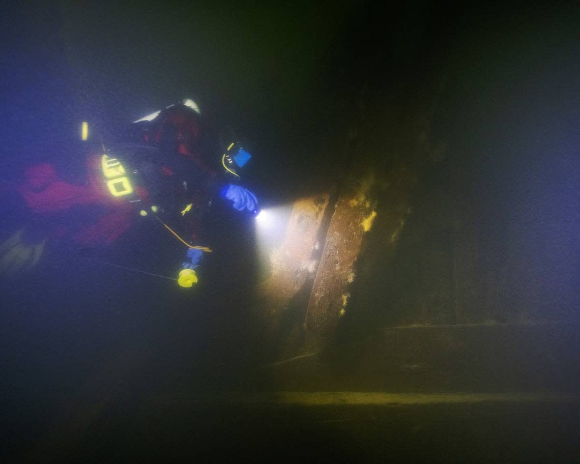 A diver shines a flashlight on the wreck of the Äpplet.