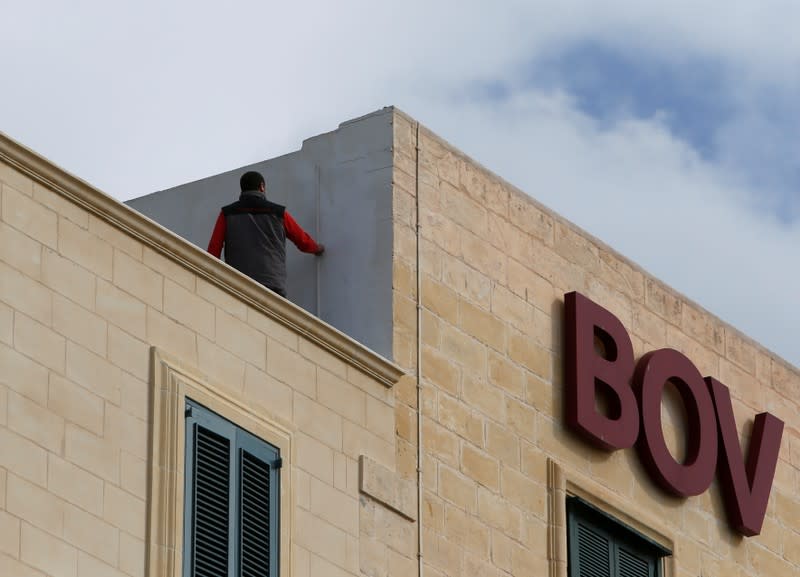 FILE PHOTO: A maintenance worker carries out repairs on the roof of a branch of Bank of Valletta in Valletta