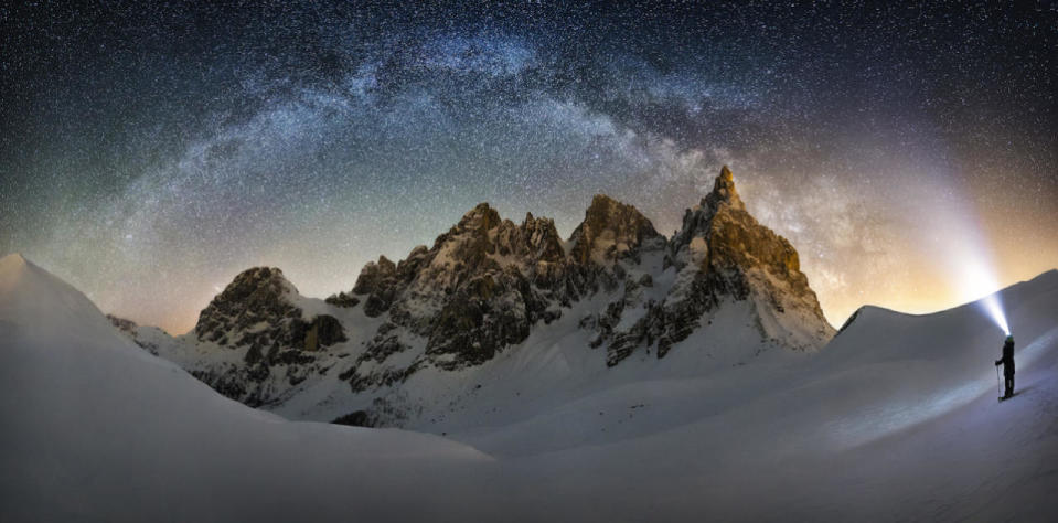 <p>The glow from a stargazer’s headlamp blends into the light of the Milky Way, arching over a mountain peak. (Nicholas Roemmelt)</p>