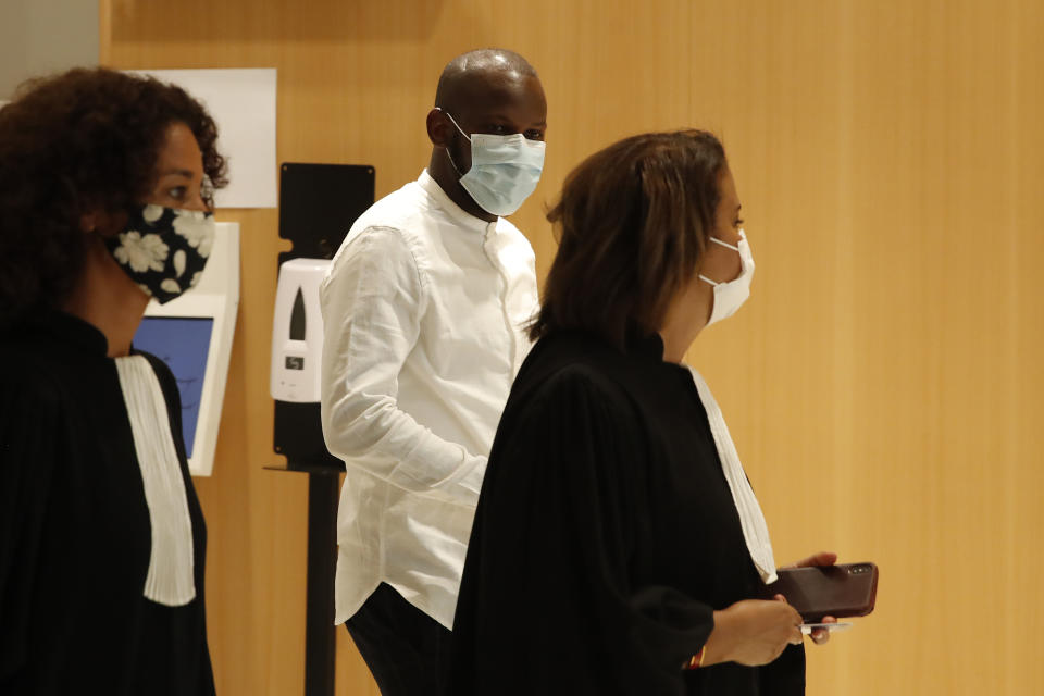 Lassana Bathily, center, who saved lives during the attack of a kosher supermarket in 2015, arrives at the courtroom for the opening of the 2015 attacks trial, Wednesday, Sept. 2, 2020 in Paris. Thirteen men and a woman go on trial Wednesday over the 2015 attacks against a satirical newspaper and a kosher supermarket in Paris that marked the beginning of a wave of violence by the Islamic State group in Europe. Seventeen people and all three gunmen died during the three days of attacks in January 2015. (AP Photo/Francois Mori)