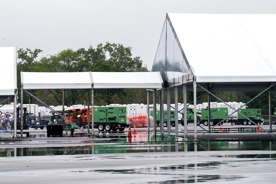 Workers disassemble hangar-sized tents, Tuesday, Oct. 4, 2022, in the parking lot of Orchard Beach in the Bronx borough of New York. Giant tents for temporarily housing migrants arriving in New York City are being moved to an island off Manhattan from a remote corner of the Bronx, after storms raised concerns over flooding at the original site. (AP Photo/Julia Nikhinson)