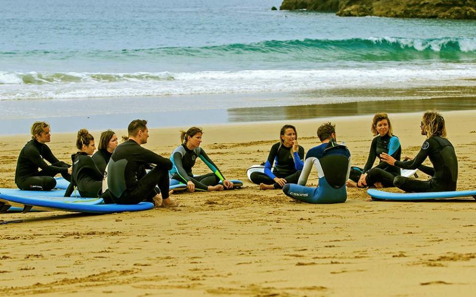 Guests from Soul & Surf talk to Findlay McGlade, one of the instructors, on the beach - DTL PHOTOGRAPHY