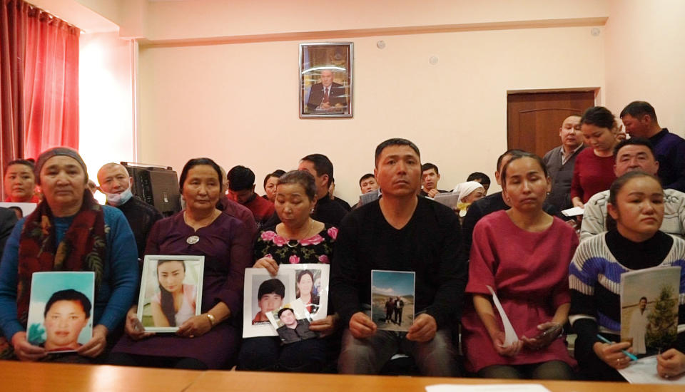 In this Dec. 7, 2018, image made from video, relatives of people missing in China's far western region of Xinjiang hold up photos at an office of a Chinese Kazakh advocacy organization in Almaty, Kazakhstan. The Kazakhstan Foreign Ministry says China is allowing more than 2,000 ethnic Kazakhs to abandon their Chinese citizenship and leave the country, a sign that Beijing may be starting to feel a mounting backlash against a sweeping crackdown on Muslims in its far west region of Xinjiang. (AP Photo/Dake Kang)