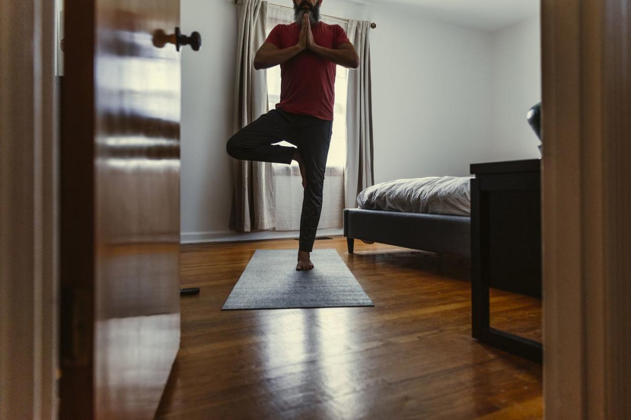 mature man practicing yoga in bedroom