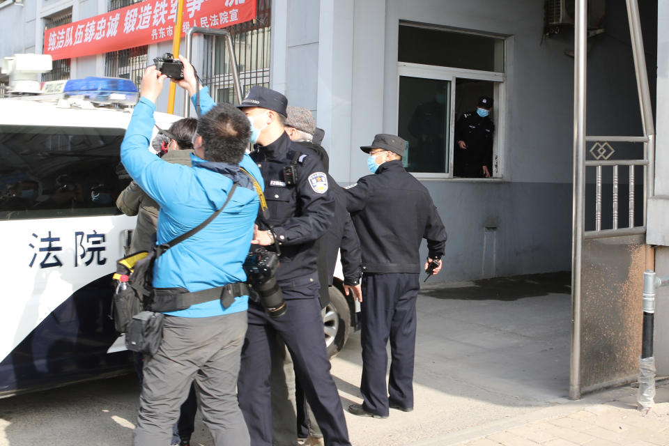 Security officers stand guard as a police van arrives at a court building in Dandong in northeastern China's Liaoning Province, Friday, March 19, 2021. China was expected to open the first trial Friday for Michael Spavor, one of two Canadians who have been held for more than two years in apparent retaliation for Canada's arrest of a senior Chinese telecom executive. (AP Photo/Ken Moritsugu)