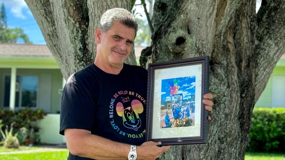 Jamie Solomon holds up a photo of his family of choice on one of their Disney trips together.