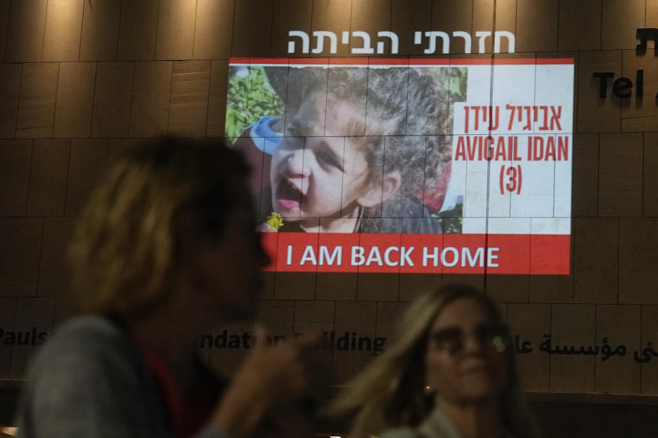 People walk past an image of 4-year-old Abigail Edan, a hostage held by Hamas who was released on Sunday, projected onto a building in Tel Aviv, Sunday, Nov 26, 2023. Edan's parents were both killed by Hamas militants in the same attack in which she was kidnapped, a cross-border assault Oct. 7 that prompted Israel to declare war on Hamas. (AP Photo/Ariel Schalit)