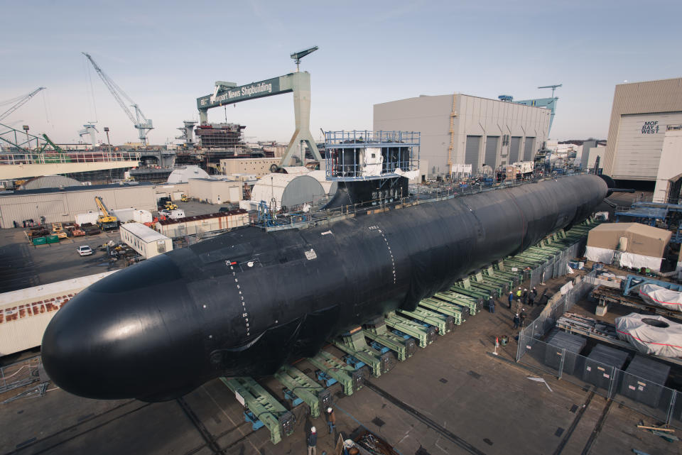 The USS Delaware in dry dock at a shipyard during the day.