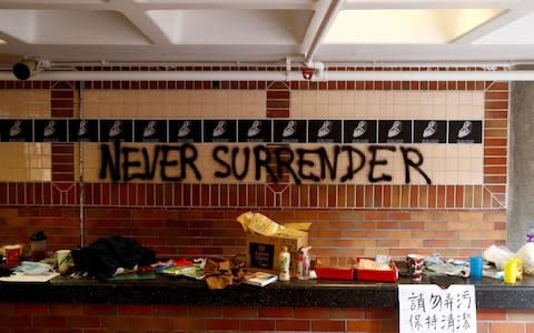 The slogan "Never Surrender" is spray painted on a wall in the besieged Hong Kong Polytechnic University (PolyU) in Hong Kong, China - Credit: REUTERS