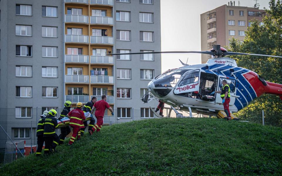 Firefighters carry a stretcher to a waiting helicopter at the scene where a fire broke out in an apartment block - AFP