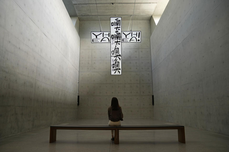 A woman looks at the artwork "Crucified TVs – Not a Prayer in Heaven" created by South Korea artist Chang Young-hae, inside the "M+" visual culture museum during a media preview in the West Kowloon Cultural District of Hong Kong, Thursday, Nov. 11, 2021. Hong Kong's swanky new M+ museum _ Asia's largest gallery with a billion-dollar collection _ is set to open on Friday amid controversy over politics and censorship. (AP Photo/Kin Cheung)