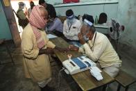 An election officer wearing a face shield as a protective measure against the coronavirus applies indelible ink on the finger of an elderly voter at a polling station, during the first phase of state elections at Paliganj, in the eastern Indian state of Bihar, Wednesday, Oct. 28, 2020. With an overall declining coronavirus positive trend, Indian authorities decided to hold the first state legislature election since the outbreak of COVID-19. People began voting Wednesday in the country’s third largest state Bihar with of a population of about 122 million people. (AP Photo/Aftab Alam Siddiqui)