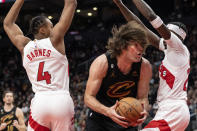 Cleveland Cavaliers' Robin Lopez, center, drives between Toronto Raptors' Scottie Barnes (4) and Chris Boucher, right, during second-half NBA basketball game action in Toronto, Monday, Nov. 28, 2022. (Chris Young/The Canadian Press via AP)