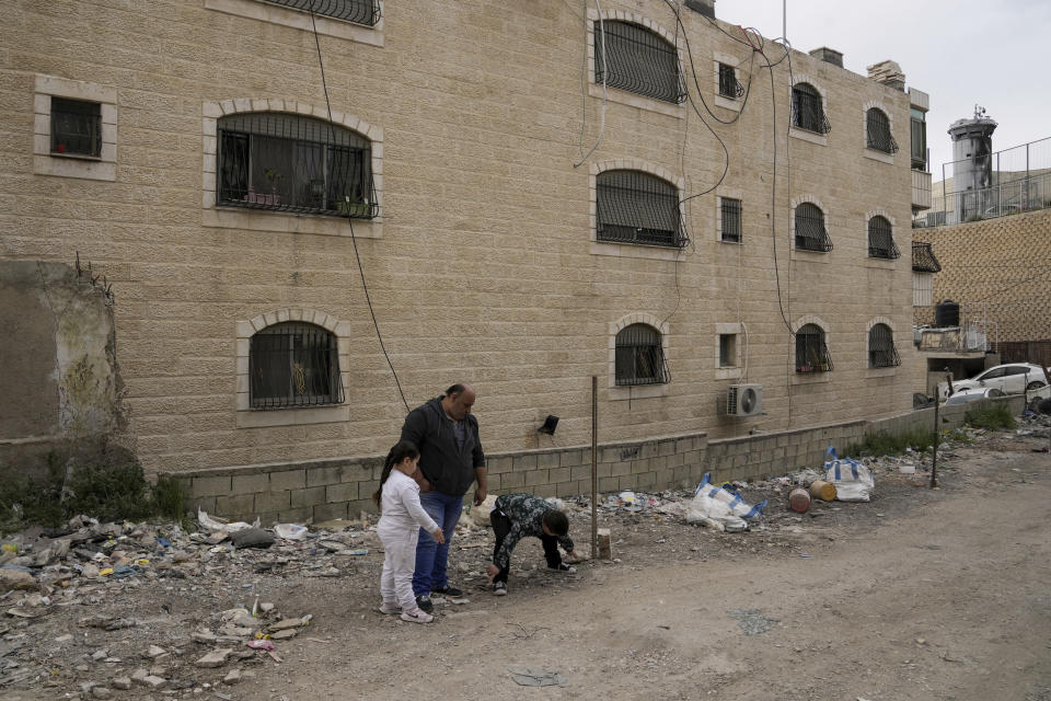 Ali Halhouli y dos parientes visitan el lugar donde Rami Halhouli, de 12 años, murió baleado la semana anterior por un policía israelí cuando lanzaba fuegos artificiales, en el campo de refugiados de Shuafat, Jerusalén Oriental, el domingo 17 de marzo de 2024. (AP Foto/Mahmoud Illean)
