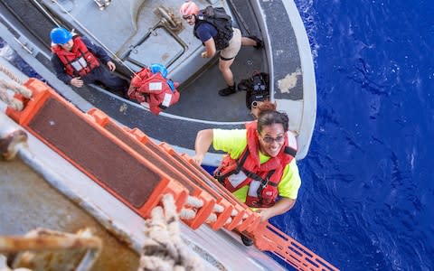 Tasha Fuiaba, an American mariner who had been sailing for five months on a damaged sailboat, climbs to safety - Credit: U.S. Navy via AP