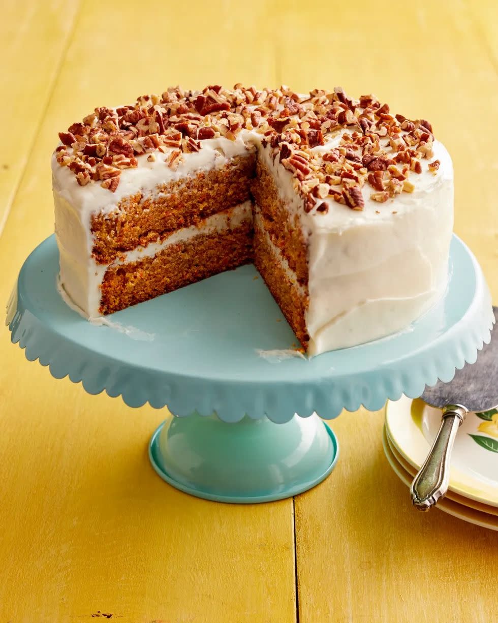 carrot cake with cream cheese frosting and nuts on cake stand