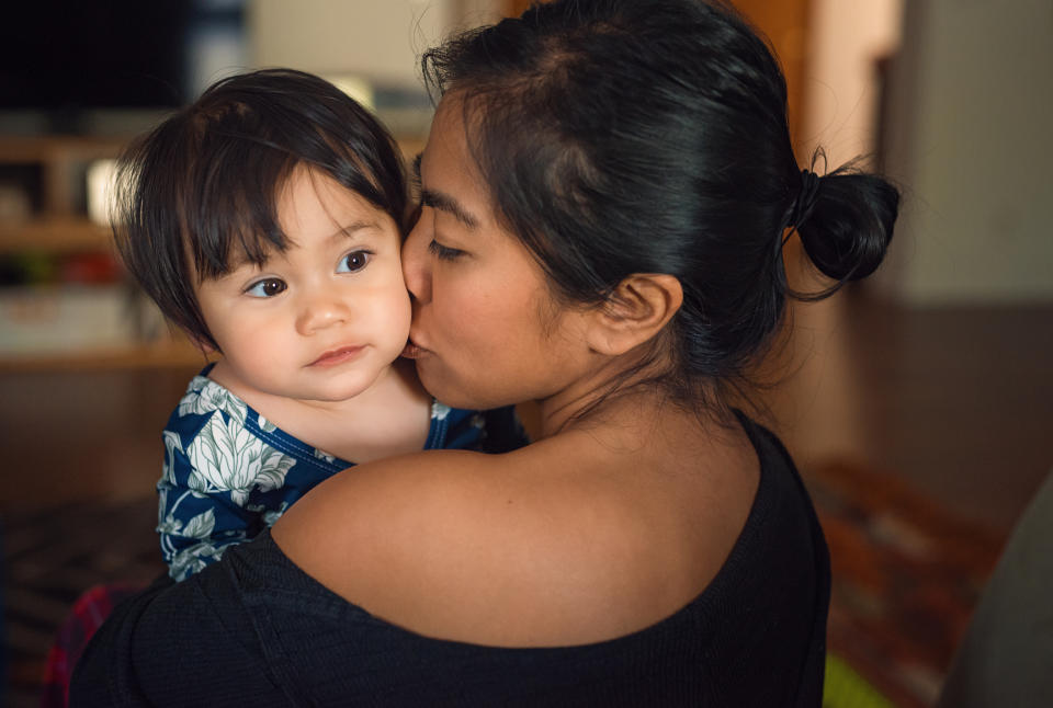 A woman is holding and kissing her toddler