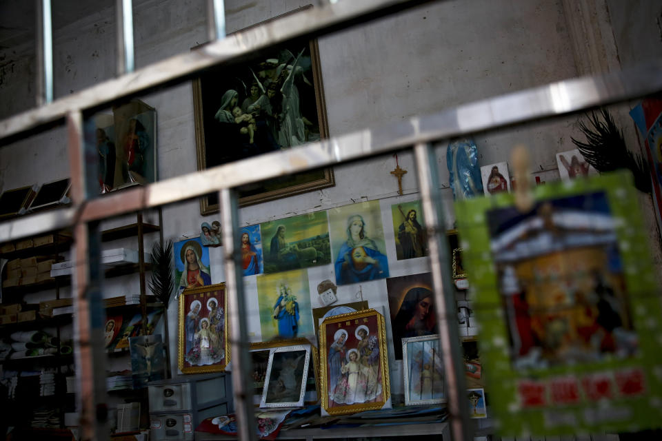 In this Tuesday, March 27, 2018, photo, Catholic religious paintings and Bibles are displayed behind bars at an underground Catholic church in Jiexi county in south China's Guangdong province. A group that monitors Christianity in China says the government is ratcheting up a crackdown on congregations in Beijing and several Chinese provinces, destroying crosses, burning Bibles and ordering followers to sign papers renouncing their faith. (AP Photo/Andy Wong)