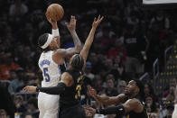 Orlando Magic forward Paolo Banchero (5) shoots over Cleveland Cavaliers forward Isaac Okoro, center, and guard Donovan Mitchell, right, in the first half of Game 7 of an NBA basketball first-round playoff series Sunday, May 5, 2024, in Cleveland. (AP Photo/Sue Ogrocki)