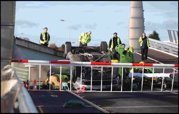 BNPS.co.uk(01202 558833)Pic: CorinMesser/BNPSFire crews extract the pensioner from her upturned Renault Clio.A pensioner had a miracle escape when she crashed her car through a safety barrier and jumped across a gap in a lifting bridge.In a scene more reminiscent to an action movie, the 86-year-old woman drove at 20mph through flashing red lights warning motorists the Poole harbour bridge was opening.Her silver Renault Clio smashed into the red and white gate and carried on along the road bridge as it was being raised.The sudden incline in the surface acted as a ramp and the pensioner's small vehicle shot off the end of the carriageway and plunged 6ft before landing on the other side.The car then overturned, trapping the shocked but injured woman inside.