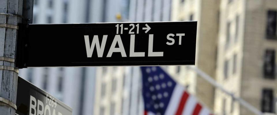 Wall street sign with focus on sign, blurred American flag background