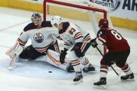 Edmonton Oilers goaltender Mikko Koskinen, left, gets help from Oilers defenseman Matt Benning (83) on a shot by Arizona Coyotes right wing Conor Garland (83) during the first period of an NHL hockey game Tuesday, Feb. 4, 2020, in Glendale, Ariz. (AP Photo/Ross D. Franklin)