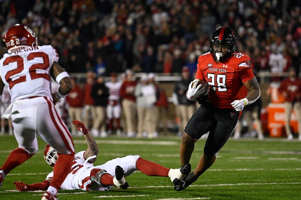 Texas Tech running back Tahj Brooks (28) carries while Oklahoma defensive back C.J. Coldon (22) and defensive back Billy Bowman defend during the first half of an NCAA college football game Saturday, Nov. 26, 2022, in Lubbock, Texas. (AP Photo/Justin Rex)