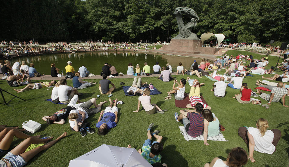 This Aug. 6, 2013 photo shows people gathered for a Chopin piano concert next to the composer's monument in the Lazienki Park in Warsaw, Poland. Free piano concerts of Frederic Chopin music are held by the Polish composer’s monument on Sundays, May through September. Open air performances are to resume in the ancient-style Amphitheater in 2014. (AP Photo/Czarek Sokolowski)