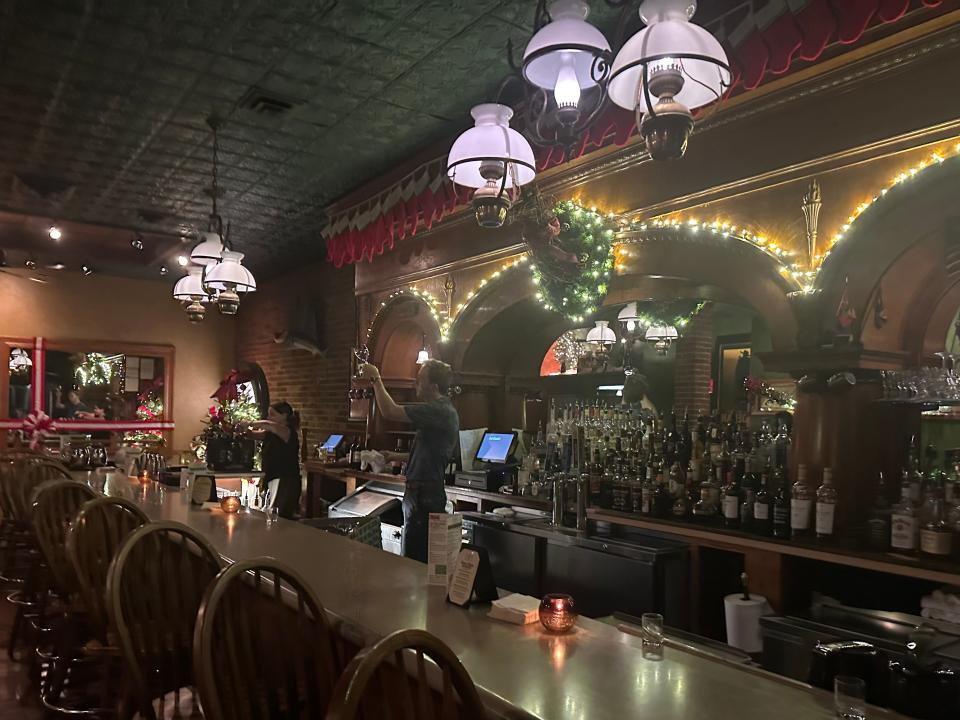 Mitch Meinert polishes stemware in the festively decorated bar area of Aunt Maude's in downtown Ames.