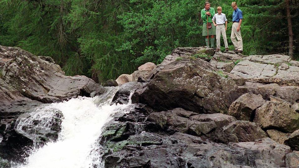 Charles, William And Harry At Balmoral standing on a rock over a waterfall