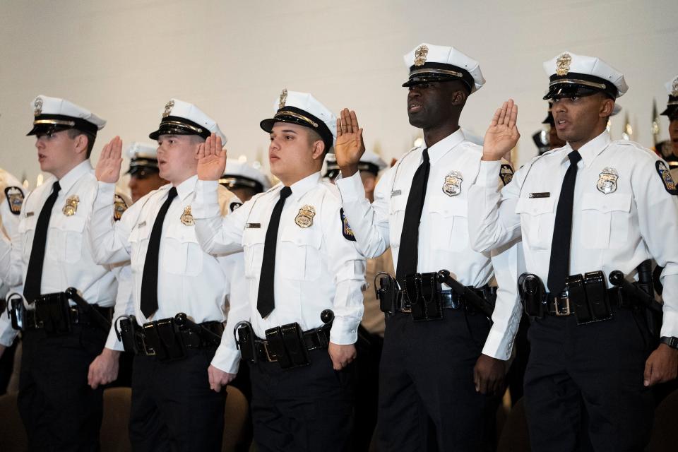 Officers from the 138th police recruit graduating class raise their hands to be sworn in Friday at the James G. Jackson Columbus Police Academy graduation ceremony.