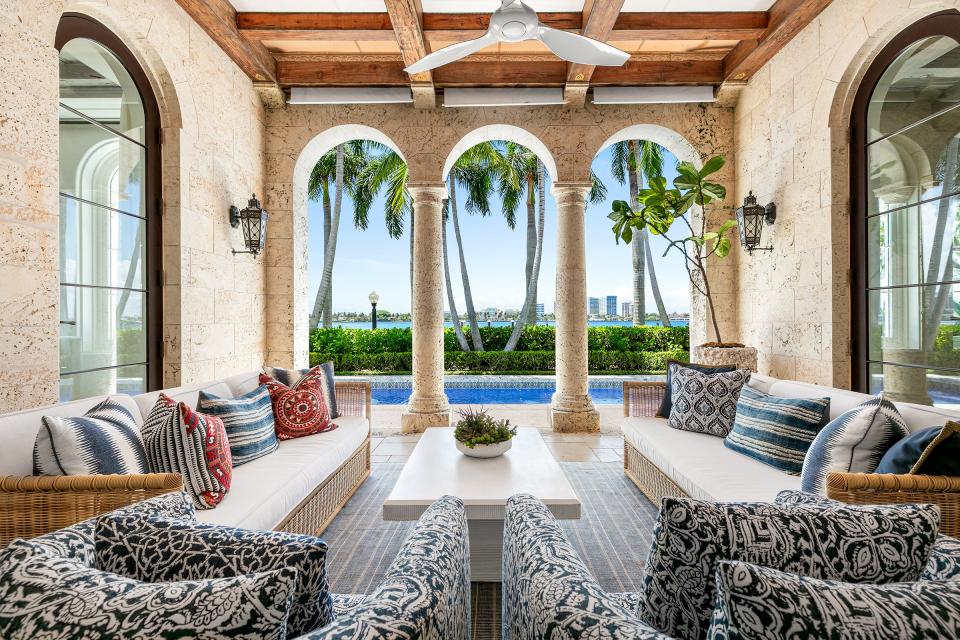 Offering a view of West Palm Beach across the lake, a covered loggia overlooks the lap pool and the lake trail at the house fashion designers Tommy Hilfiger and Dee Ocleppo Hilfiger updated on Dunbar Road. The property is listed at $35.9 million by Christian Angle Real Estate.