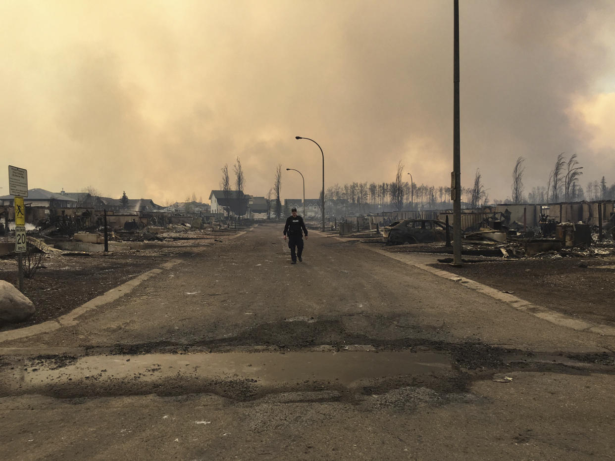 A Mountie surveys the damage on a street in Fort McMurray, Alberta, Canada in this May 4, 2016 image posted on social media. Courtesy Alberta RCMP/Handout via REUTERS   ATTENTION EDITORS - THIS IMAGE WAS PROVIDED BY A THIRD PARTY. EDITORIAL USE ONLY. TPX IMAGES OF THE DAY