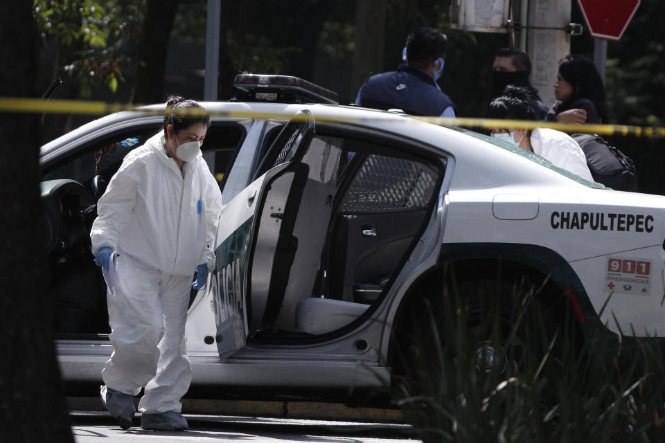 A forensic investigator inspects a police vehicle at the scene where the Mexican capital's police chief was attacked by gunmen in Mexico City, Friday, June 26, 2020. Heavily armed gunmen attacked and wounded Omar García Harfuch in an operation that left several dead. (AP Photo/Rebecca Blackwell)