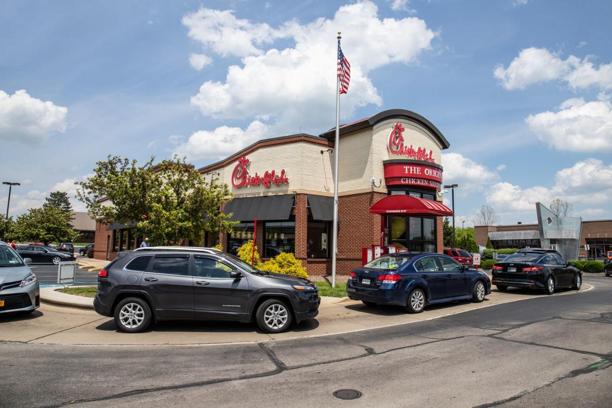 Focus on the drive-thru of a Chick-fil-A restaurant, Indianapolis, Indiana with several cars in a line on a bright, sunny day