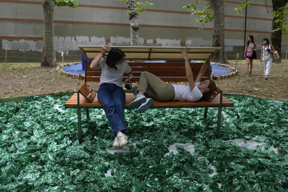 Girls take a break on a bench created by Italian designer Stefano Boeri, part of the Furniture and Design Fair exhibition in Milan, Italy, Wednesday, June 8, 2022. (AP Photo/Antonio Calanni)